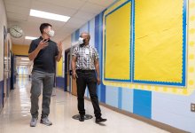 Under the careful watch of principal Keith Moore (r) and a staffer, in-person learning resumes for the first time since March at Campbell Elementary in Austin.