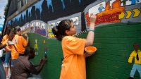 Student paint an outdoor wall mural