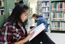 Teen reading a book on the floor of a library