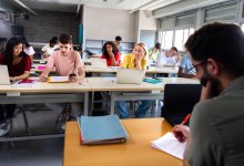 Teacher grading papers in classroom full of students