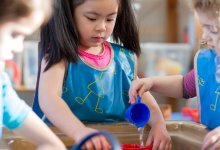 A photo of preschool students interacting with a water table