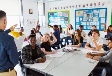 High school teacher standing at the front of the class and talking to students